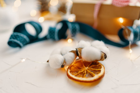 Close-up of dried orange and cotton. Christmas decorations on white table. Ribbon, garland and gift box in background. Festive still-life.の写真素材