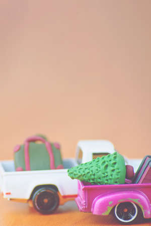 Small purple and white pickup automobiles on table. Car toy models with suitcases and christmas tree. Miniature fir and briefcases made of polymer clay. Concept of festival travel and vacation.の写真素材