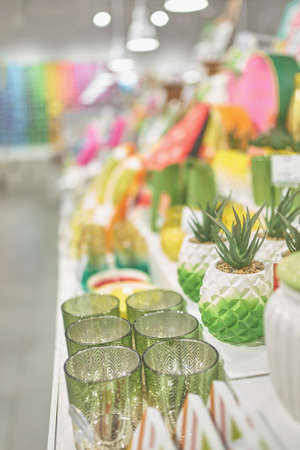 White shelf with colorful decorated dishes. Shop window of home goods store. Patterned green glasses and planters with artificial succulent.の写真素材