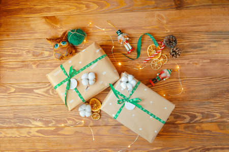 Christmas gifts on wooden table. Boxes in wrapping paper with patterns tied with ribbons with snowflakes. Toy soldiers, coffee handmade owl, cones and cotton on background. New years atmosphere.の写真素材