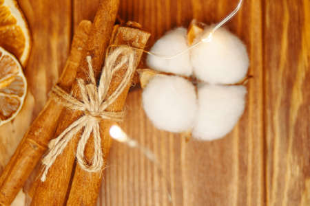 Top view of cotton boll, cinnamon sticks tied with rope. Christmas decor on wooden table. Pieces of dried oranges. Festive background.の写真素材
