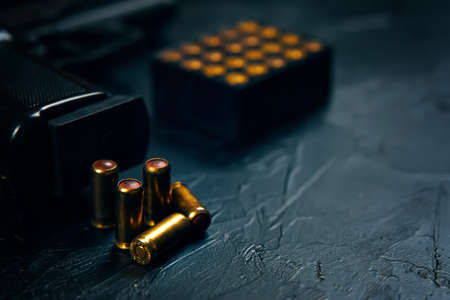 Black gun with cartridges on table. Automatic firearms with bullets. Weapons on concrete background. Pistol for defense or attack.の写真素材