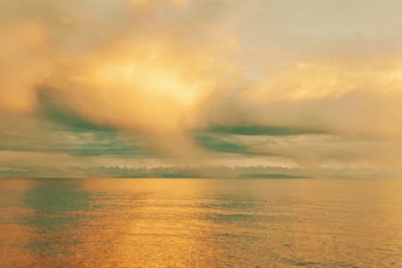 Summer landscape. Beautiful clouds over sea. Sunlight through clouds. Beach with trees on horizon. Travel background.の写真素材