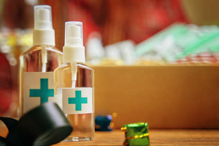 Alcohol sanitizers with red cross on wooden table. Concept of hand hygiene and prevention from viruses and bacteria. Christmas decorations and antiseptic. New Year on quarantine.の写真素材