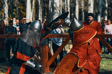 The knight in red is fighting with the knight in black. Sword fighting. Reconstruction of medieval...