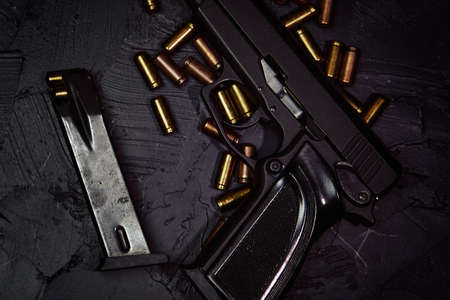 Flat lay of gun and cartridge with bullets. Weapons on concrete table. Pistol for defense or attack. Concept of crime ammunition and physical evidence. Firearms on dark background.の写真素材