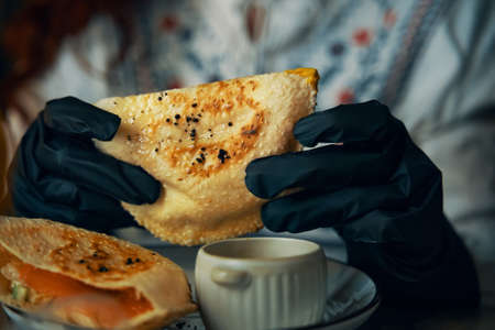 Female hands in black gloves are holding traditional pitas sandwich. Dish of corn bread with fish and salad inside. Cafe menu. Delicious lunch in restaurant.の写真素材