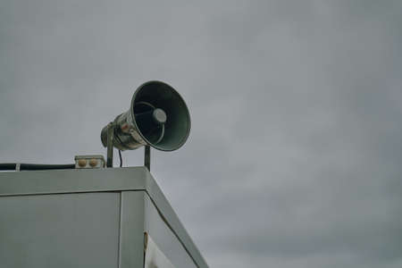 Megaphone on cloudy sky background. Emergency alert siren. City hazard warning system. Providing security in town, notification of emergencies. Copy space for text.の写真素材