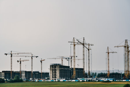 Building site background with copy space. Industrial construction cranes on background of foggy sky....