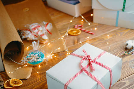 Christmas gift, gingerbread, sweets, craft wrapping paper and garlands on wooden table. Festive mood and holiday decorations. Surprise for New Year.の写真素材