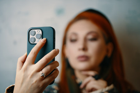 Close-up of females hand with mushrooms ring holding smartphone in case. Red hair woman takes selfie on iPhone 13 pro. Gadget with triple-lens camera. Bishkek, Kyrgyzstan - January 24, 2022のeditorial素材