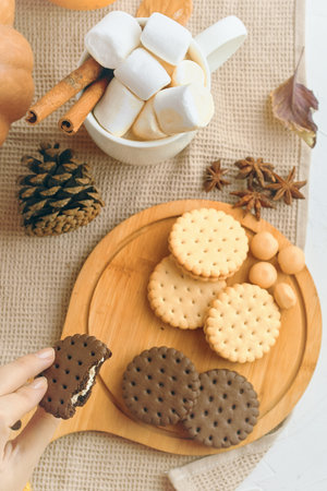 Delicious assortment of cookies and marshmallows on a wooden board, perfect for autumnal treat vibes.の写真素材