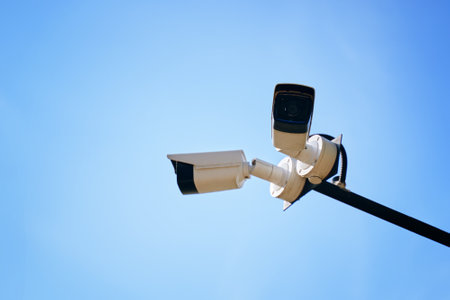A stunning and striking view of modern surveillance cameras positioned perfectly under a clear blue skyの写真素材