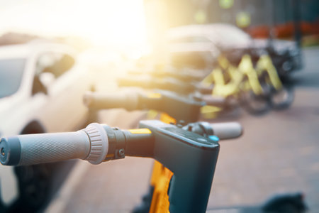 A row of electric scooters with automotive tires and electrical wiring are parked on the side of the road, featuring bicycle handlebars and automotive lightingの写真素材