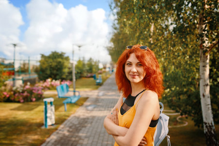 A cheerful woman strolls through a sunlit park, surrounded by vibrant greenery, blooming flowers, and natures beautyの写真素材