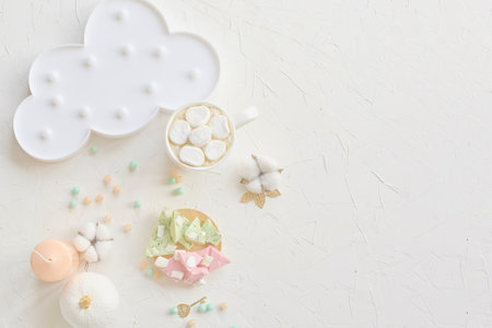 Charming pastel-colored dessert setup featuring marshmallows, a cloud plate, and decor on a white background.の写真素材