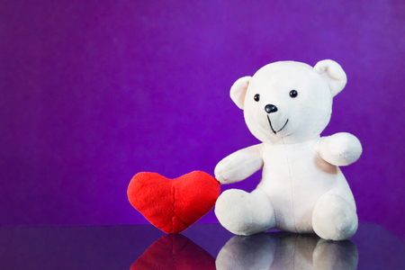 Teddy bear with heart sitting on the glass with  purple background. Get Taste Forever Valentine.の写真素材