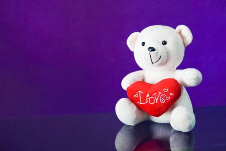 Teddy bear with heart sitting on the glass with  purple background. Get Taste Forever Valentine.の写真素材