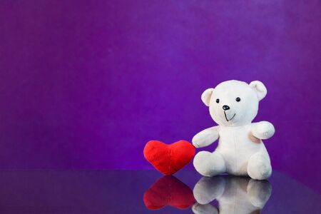 Teddy bear with heart sitting on the glass with  purple background. Get Taste Forever Valentine.の写真素材