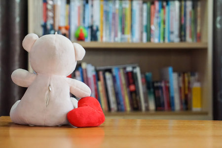 Teddy bear with a heart sitting on the wooden floor with  books background. Taste Forever Valentineの写真素材