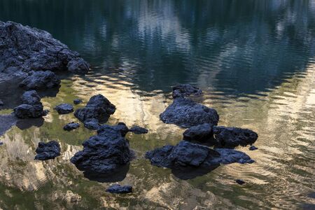 Optical effect on Lake Braies at sunset. The mountains illuminated by the sun reflect on the surface...