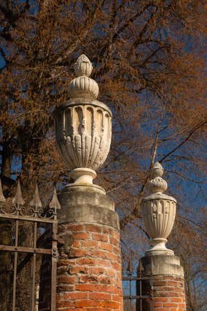 The entrance to Querini Park. Columns made with bricks. On the top, decorative elements of classical inspiration carved on stone. Trees stand out against a deep blue sky. Winter atmosphere. Vicenza.の写真素材