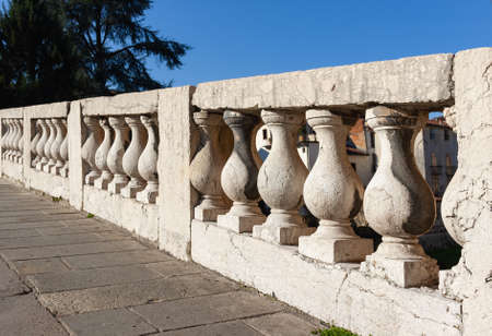 A long stretch of the elegant balustrade of the Ponte San Michele in Vicenza. This structure is inspired by the bridges of Venice. In the background a glimpse of the buildings of the historic center.の写真素材