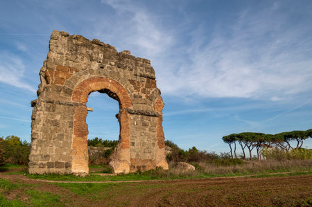 Park of the aqueducts ruins of the Claudius aqueduct, park of Appia Antica Rome particular of arch detail of the bricks in a sunny day and blue sky, with beautiful landscape.の写真素材