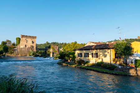 The beautiful medieval village of Borghetto di Valeggio sul Mincio. Detail of the medieval tower river with the bridge and flowering gardens. Province of Verona, Veneto, Italyのeditorial素材