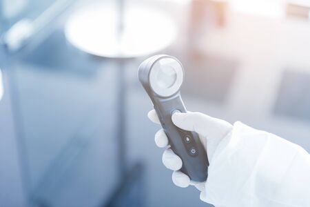 hand holding thermometer infrared in sterile suits