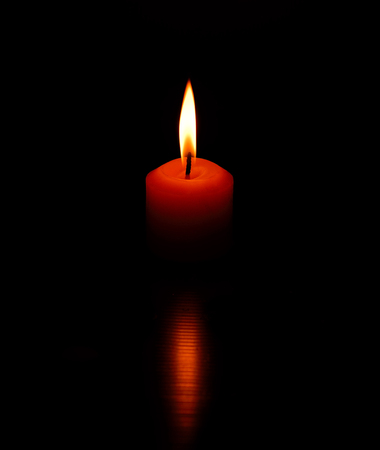 One candle burning bright on black background.の写真素材