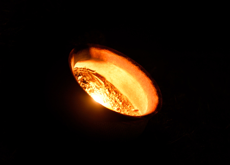 One candle burning bright in a clay pot on a black background.の写真素材