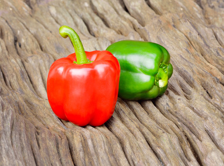 Green and red bell pepper on wood backgroundの写真素材