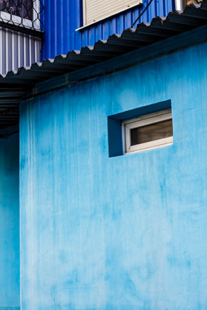 Blue wall of the house with a closed window left and detailsの写真素材