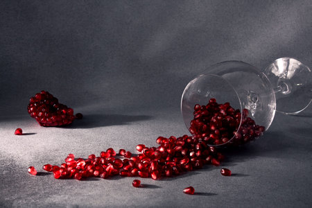 Pomegranate seeds in a wine glass and ripe pomegranate pieces nearby. Pomegranate wine. The concept of romance. Healthy food concept. Seasonal winter fruits. Source of iron.の写真素材
