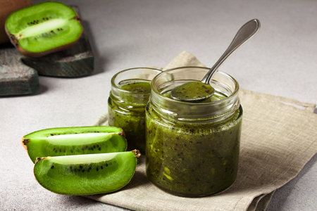 Homemade kiwi jam in a jar and kiwi slyces on concrete background with copy spaceの写真素材