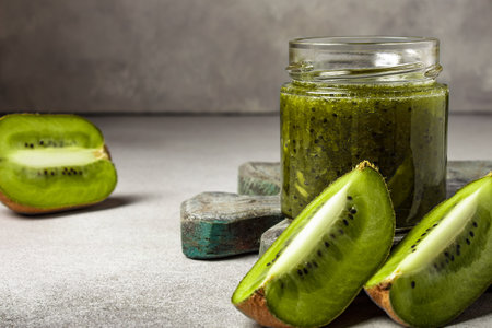 Homemade kiwi jam in a jar and kiwi slyces on concrete background with copy spaceの写真素材