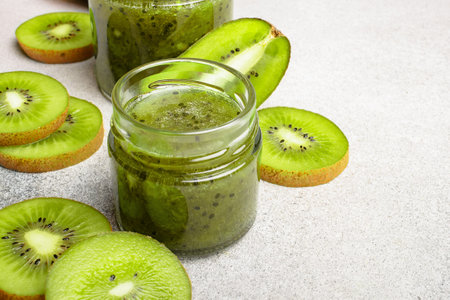 Homemade kiwi jam in a jar and kiwi slyces on concrete background with copy spaceの写真素材