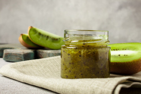 Homemade kiwi jam in a jar and kiwi slyces on concrete background with copy space.の写真素材