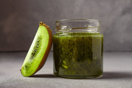Homemade kiwi jam in a jar and kiwi slyces on concrete background with copy space.の写真素材