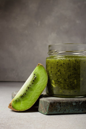 Homemade kiwi jam in a jar and kiwi slyces on concrete background with copy space.の写真素材