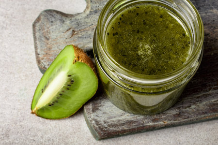 Homemade kiwi jam in a jar and kiwi slyces on concrete background with copy space.の写真素材