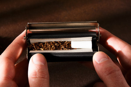 Hand-rolled cigarette, rolling machine, scattered tobacco on background, cigarette roll with filter, cigarette filters.の写真素材
