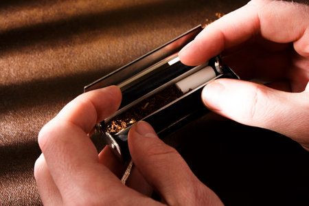Hand-rolled cigarette, rolling machine, scattered tobacco on background, cigarette roll with filter, cigarette filters.の写真素材