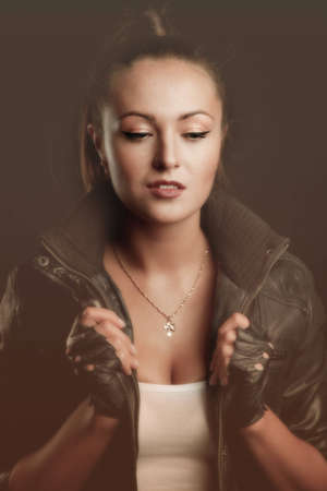 Young brunette lady in black jacket posing on grey backgroundの写真素材