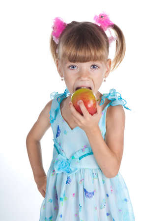 Pretty little girl in a blue dress with an apple in her handの写真素材