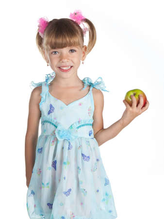 Pretty little girl in a blue dress with an apple in her handの写真素材