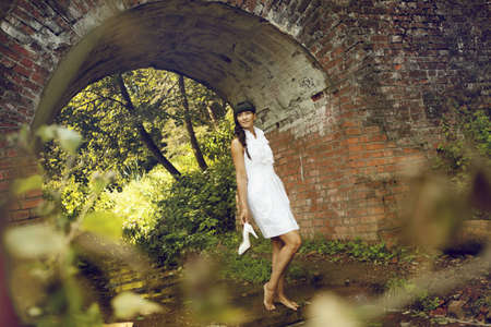 young woman standing in the water against a brick archの写真素材