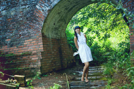 young woman standing in the water against a brick archの写真素材