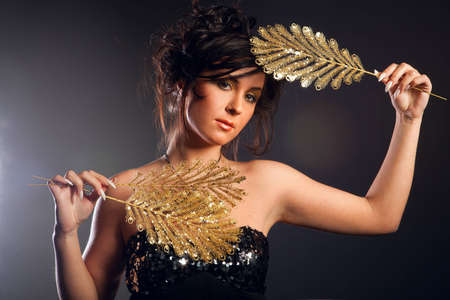 young girl holding an ornament of gold feathersの写真素材